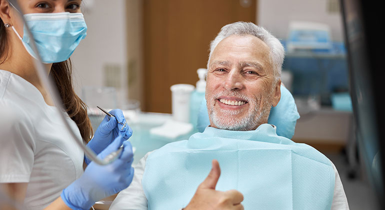 an older man smiling at the dentist